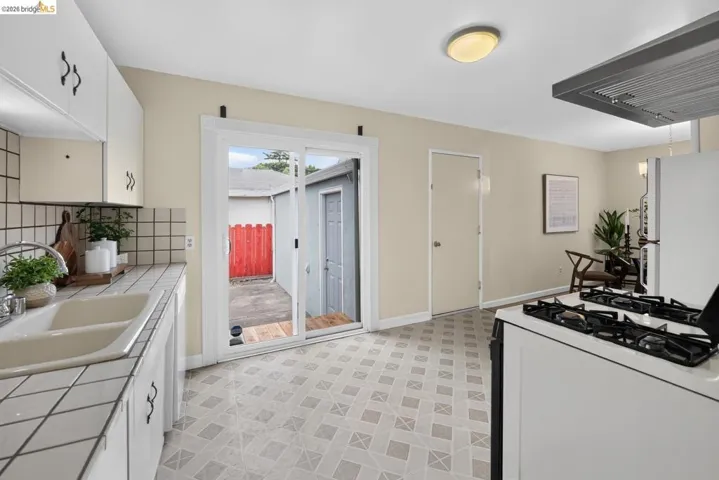 Kitchen featuring white cabinetry with dark hardware, a double basin sink, and white tiled countertops