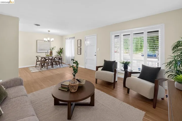 Open-concept living space featuring wood-finish flooring, plantation shutters, and a dining area with a chandelier