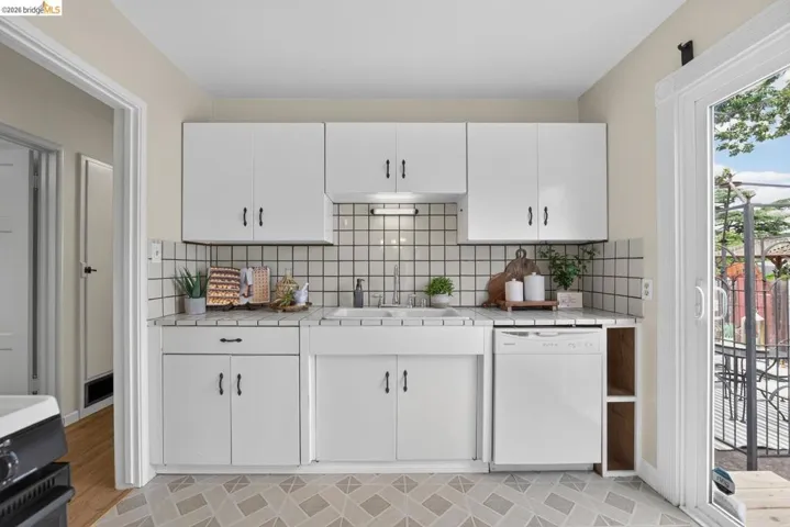 Kitchen area featuring white cabinetry with dark hardware, a farmhouse-style sink, and geometric tile flooring