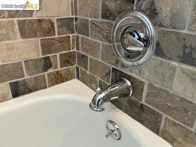 Tub surround featuring rectangular stone-look tiles in varied earthy tones