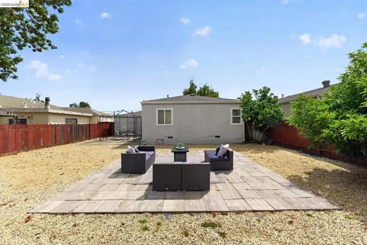 Spacious backyard featuring a large flagstone patio, gravel landscaping, and established perimeter trees