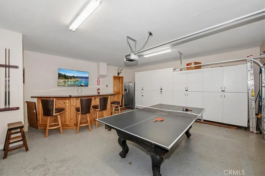 Garage with epoxied floor used as a game room. Bar with wine fridge and dishwasher. Custom cabinets.