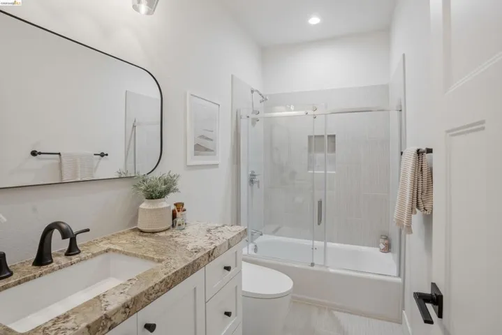 Bathroom featuring a single vanity with a stone countertop, built-in sink, and matte black faucet