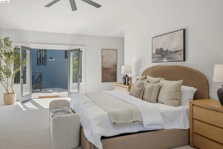 Bedroom featuring double glass-paneled French doors opening to an outdoor patio with a corrugated exterior wall