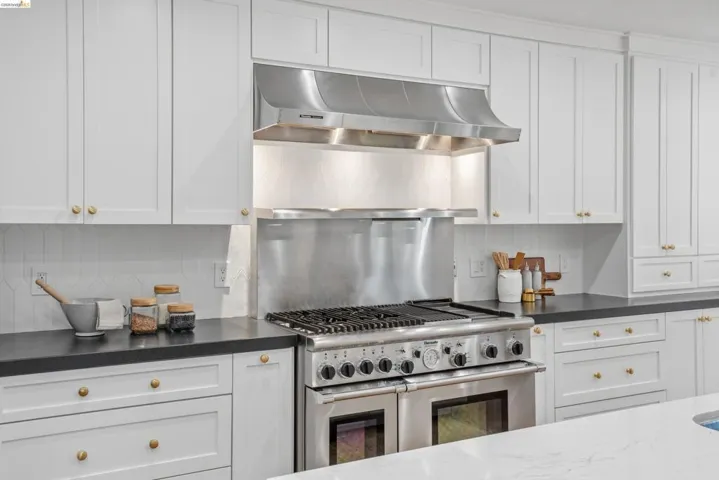 Professional-grade stainless steel range with a coordinating range hood, framed by white shaker-style cabinetry