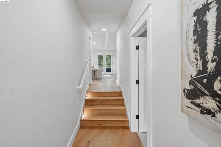 Hardwood flooring extending through the hallway and up the illuminated staircase