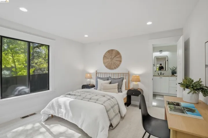 Bright sleeping area featuring recessed lighting, a large window with white trim, and light-toned carpeting