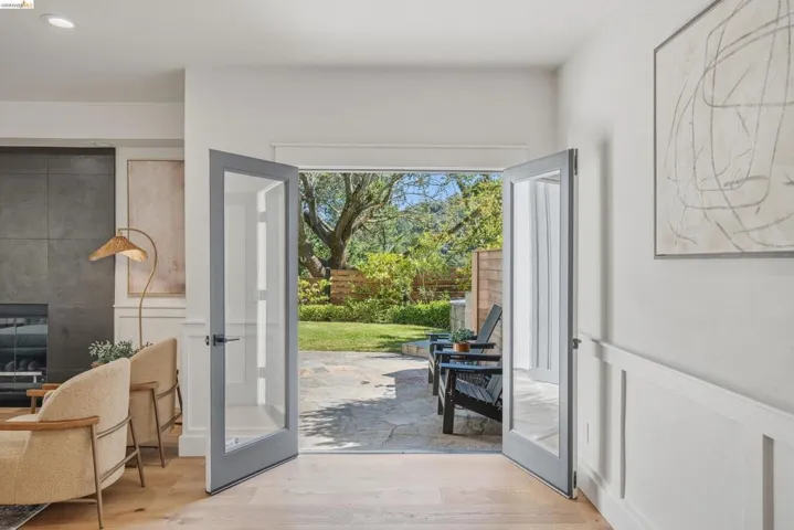 French doors opening to a stone patio and mature landscaping