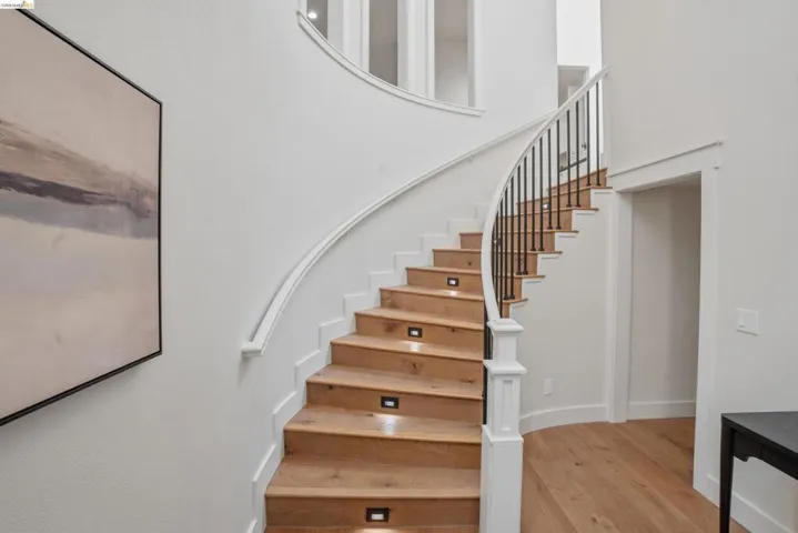 Curved staircase featuring wood-finish treads, black metal balusters, and white risers