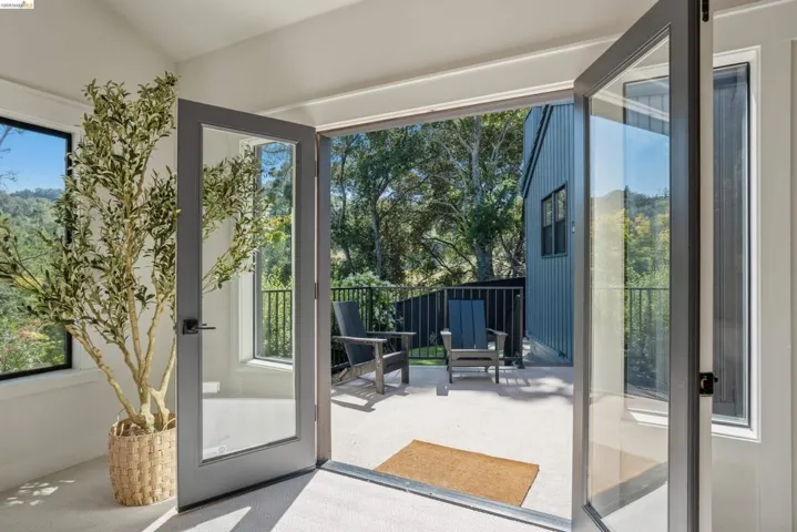 Full-light French doors open to a private outdoor patio with a black metal railing
