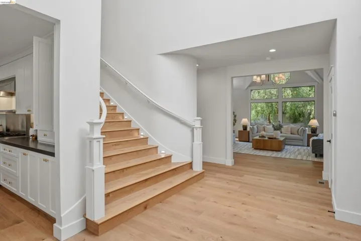 Curved staircase with wood-finish treads and white risers, featuring integrated step lighting and a white handrail