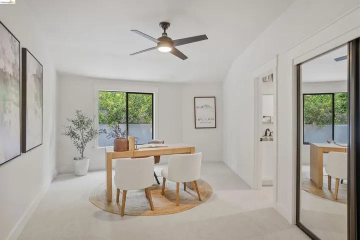 Bright room featuring a large window with exterior greenery, a ceiling fan with integrated lighting, and neutral carpeting