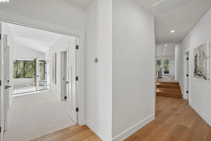 Interior hallway featuring wood-finish flooring, white paneled doors with matte black hardware, and recessed lighting