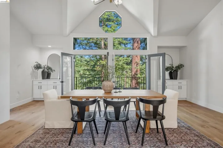 Vaulted ceilings with exposed beams, wood-finish flooring, and white walls create a bright interior