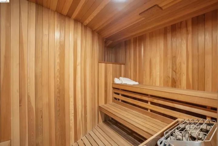 Custom sauna featuring natural wood paneling, slatted wood benches, a slatted wood floor, and a built-in heater