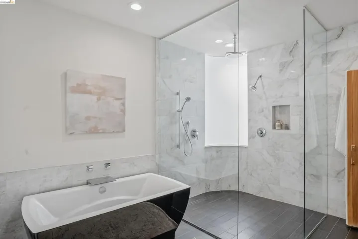 Spacious bathroom featuring a freestanding soaking tub, a frameless glass shower enclosure, a rain showerhead, a hand-held shower fixture, and recessed lighting