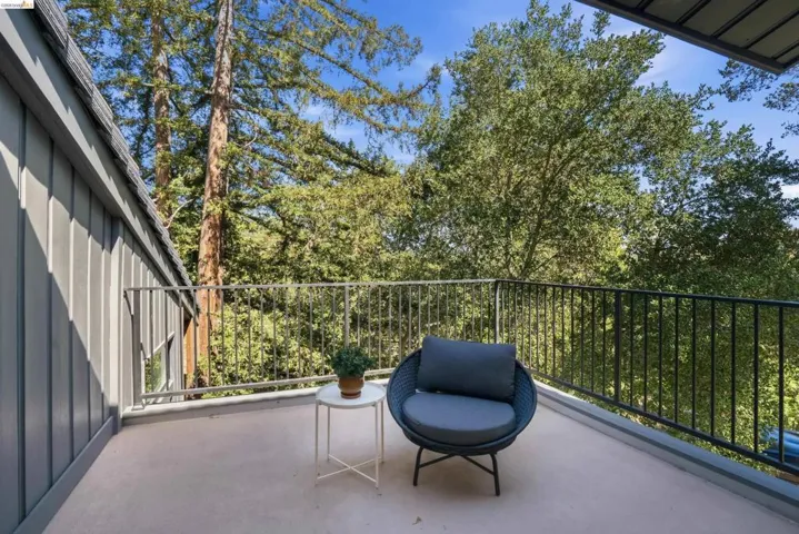 Exterior balcony featuring a metal railing and a serene tree-lined backdrop