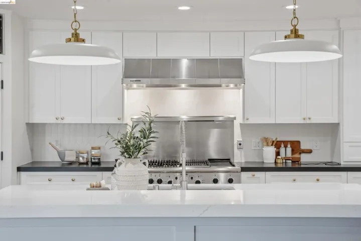 Gourmet kitchen featuring a stainless steel range with a professional-grade hood, white shaker cabinetry, dark countertops, and a full-height tile backsplash