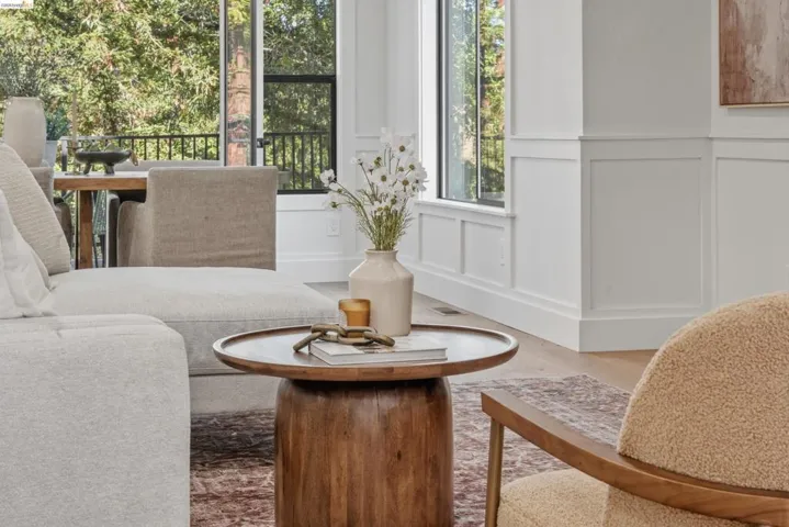 Living area featuring large windows with black framing, white wainscoting, and light wood-finish flooring