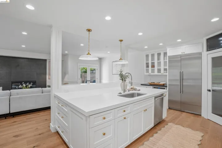 Kitchen island featuring a stainless steel sink, white countertop, and gold-toned hardware