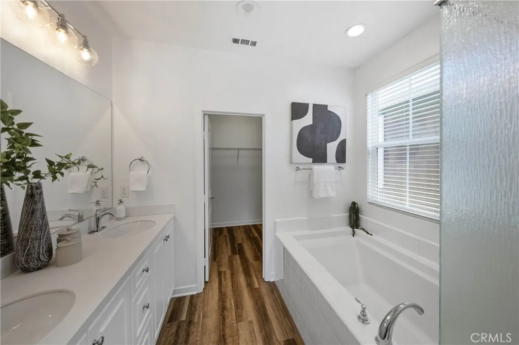 Primary bathroom with dual vanity sinks, tub & walk-in shower