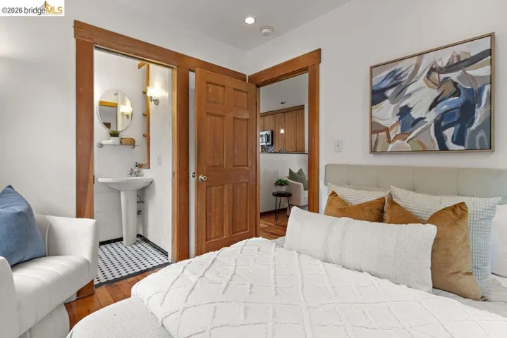 Bedroom featuring wood-finish flooring, a contemporary upholstered headboard, and a built-in shelf