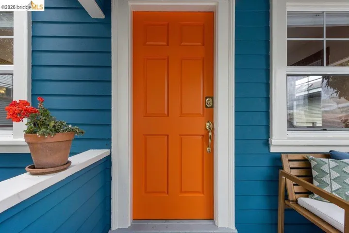 Vibrant orange paneled entry door with polished brass hardware