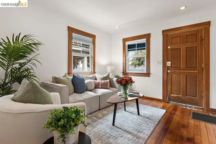 Living area featuring rich wood-finish flooring, a paneled wood-finish entry door, and recessed lighting