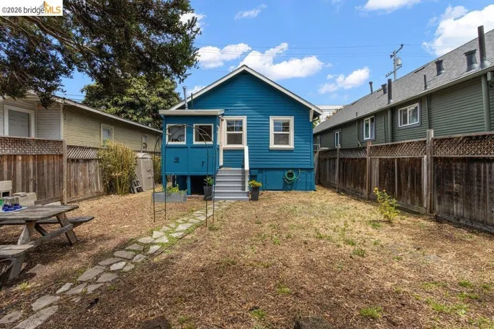 Rear exterior featuring blue siding, white trim windows, and a raised enclosed porch with stairs