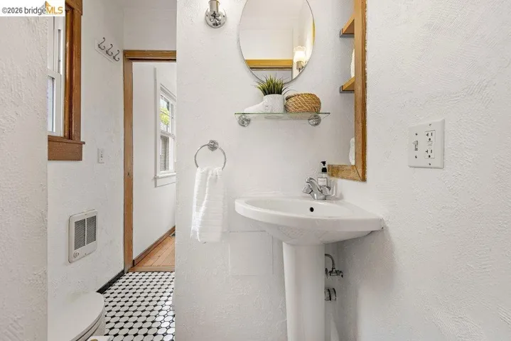 Pedestal sink with chrome faucet, circular mirror, and glass shelf