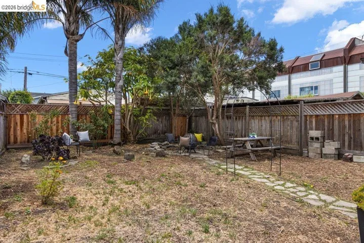 Spacious outdoor area featuring a stone pathway, mature trees, and privacy fencing