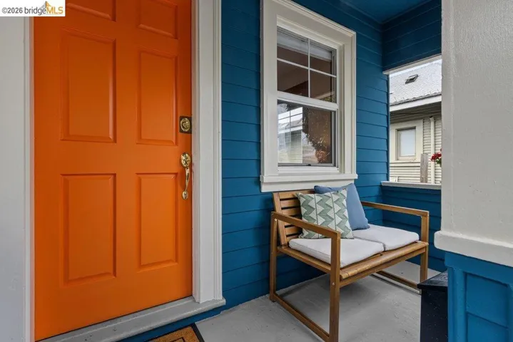 Vibrant paneled entry door with polished brass hardware, complemented by blue horizontal siding and crisp white trim