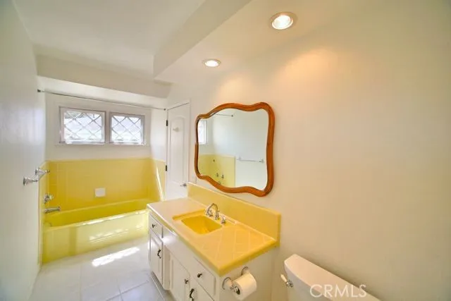 Secondary main floor full bath with tub in shower and beautifully accented yellow countertops and shower tile.