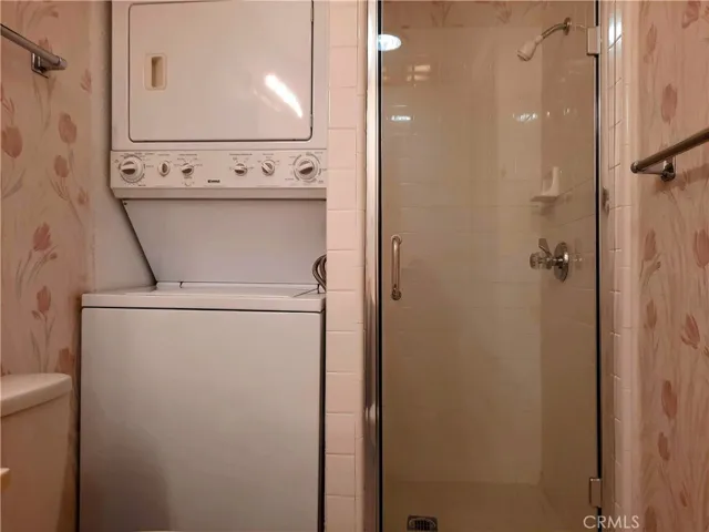 Bathroom w/ walk-in shower and stacked washer & dryer