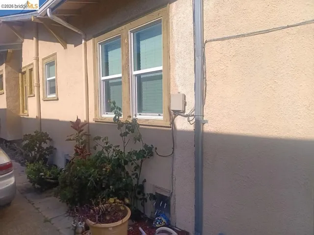 Stucco exterior featuring multiple windows with natural wood trim and white frames