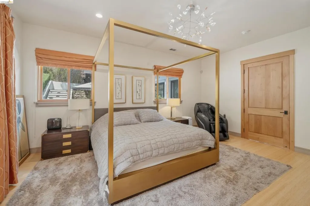 Bedroom featuring wood-finish flooring, a contemporary chandelier, two windows with blinds, and a solid wood door
