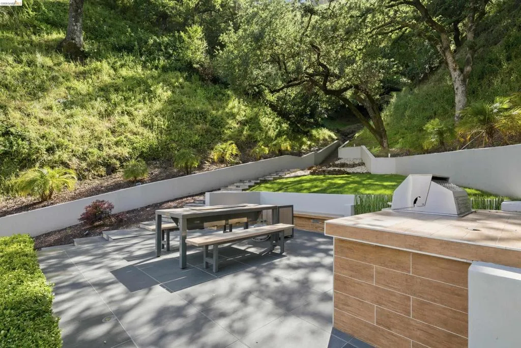 Outdoor entertaining area with a built-in barbecue station, tile-finish countertop, and wood-look paneling