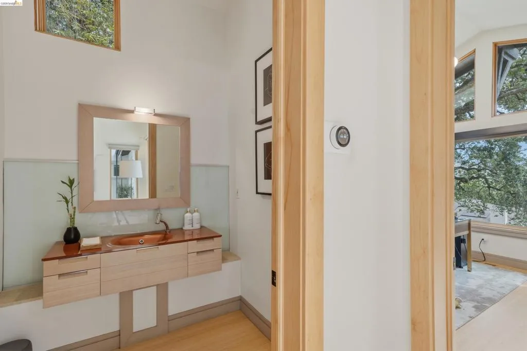 Floating vanity with a built-in vessel sink and a wall-mounted faucet, complemented by a framed mirror with integrated lighting