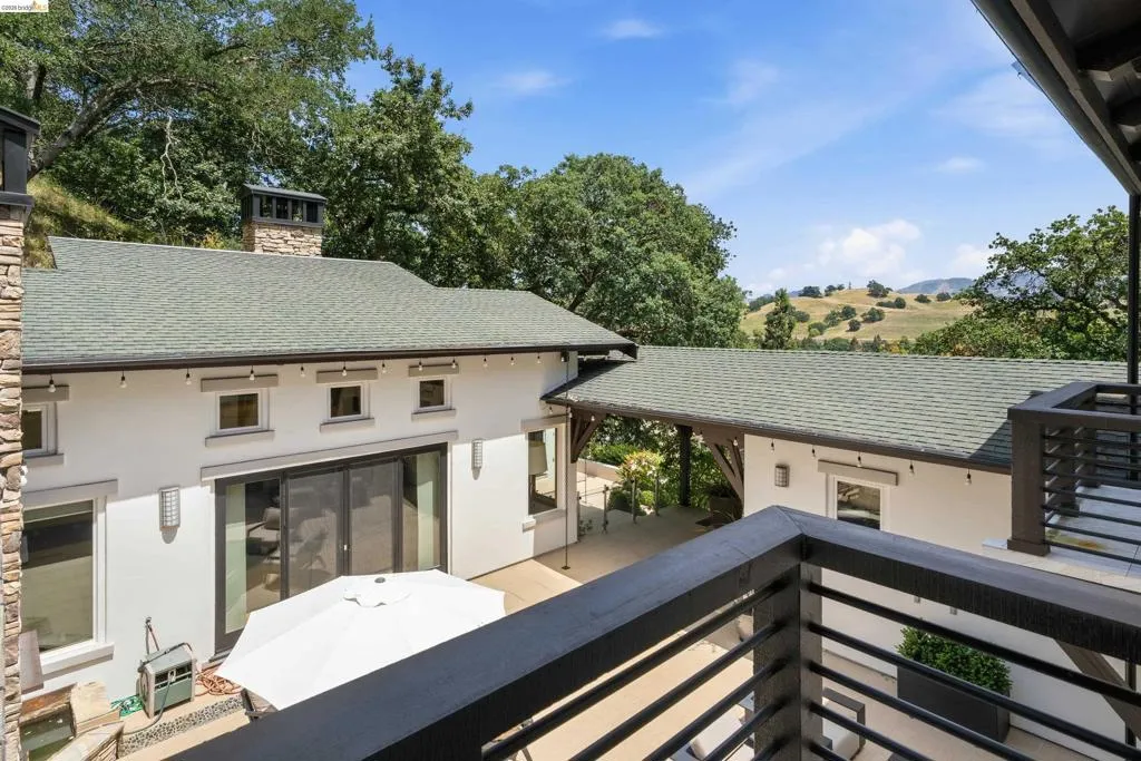 Exterior stucco finish with a green shingle roof and a stone-clad chimney