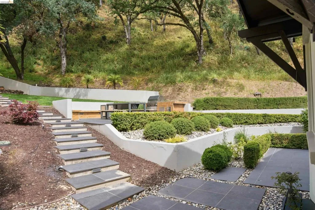 Tiered outdoor landscaping with integrated stone steps and a built-in barbecue area