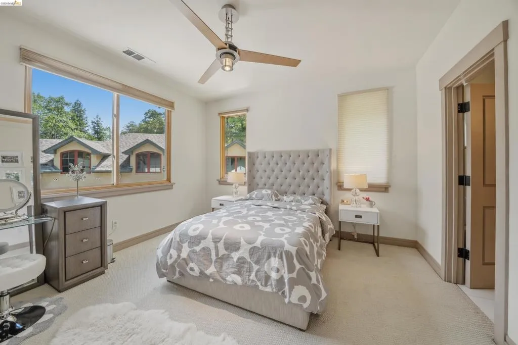 Carpeted bedroom featuring a large picture window, a secondary vertical window, and a contemporary ceiling fan