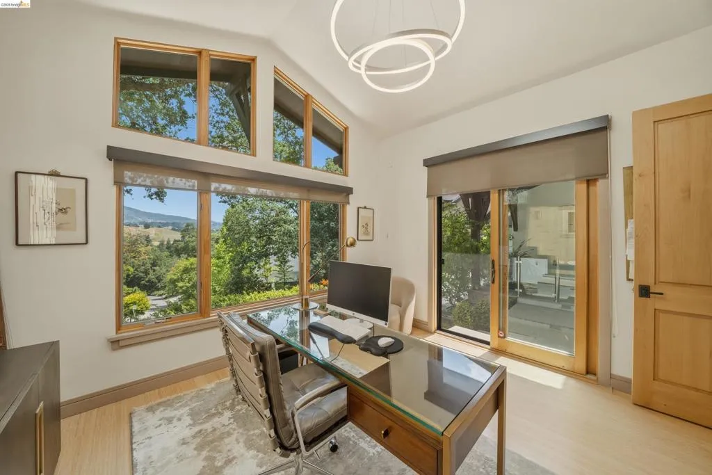 Room featuring a striking vaulted ceiling, expansive window array with wood-finish framing, and a modern circular chandelier