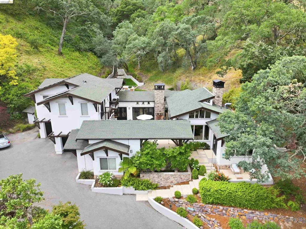 Contemporary residence featuring multiple gabled roofs, two stone chimneys, and expansive windows