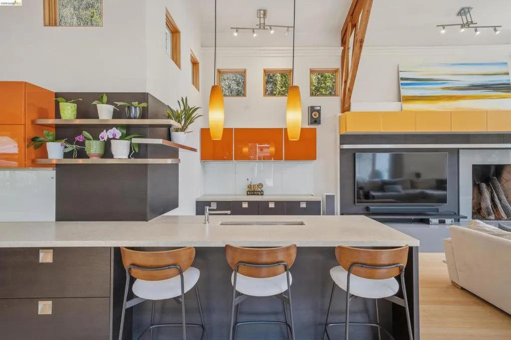 Open-concept kitchen featuring an island with built-in seating, quartz countertops, modern pendant lighting, and warm wood-finish flooring