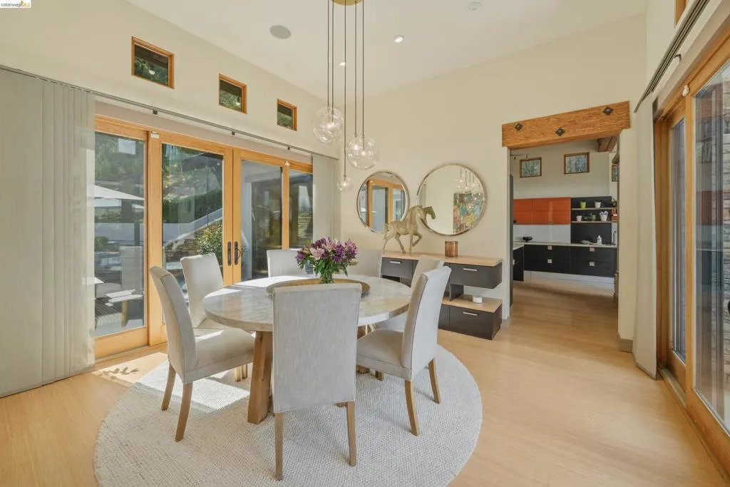 Dining area featuring light wood-finish flooring, a contemporary chandelier, multiple transom windows, and sliding glass doors providing access to the exterior