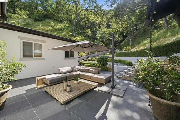 Expansive outdoor patio featuring large format tile flooring and a terraced hillside landscape