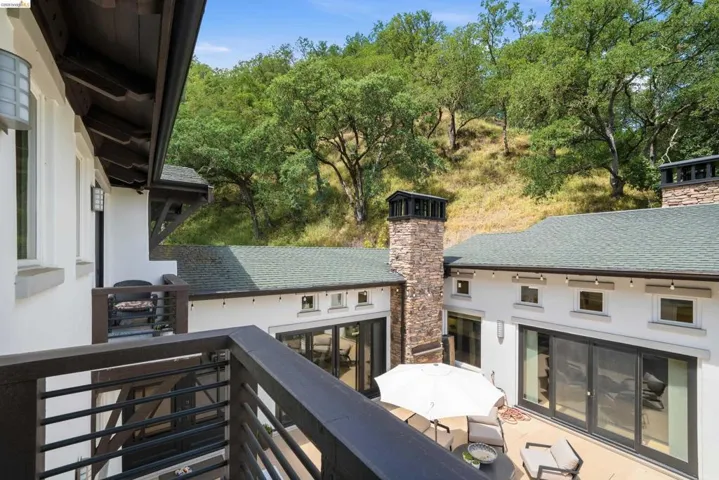 Exterior patio with multiple sliding glass doors, a stone-clad chimney, and a green shingle roof