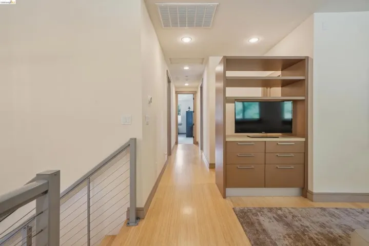 Hallway featuring wood-finish flooring, recessed lighting, and a built-in media cabinet with shelving and drawers