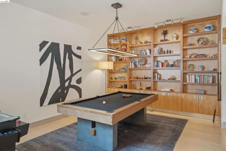 Entertainment room featuring a pool table with a black felt playing surface and concrete-style base