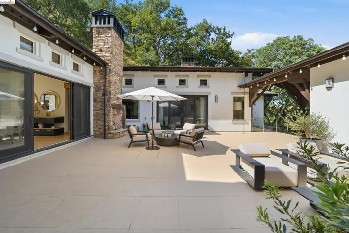 Expansive paved patio featuring a stone-clad fireplace and outdoor lighting